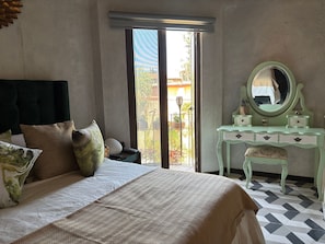 Un dormitorio con cama, cómoda, espejo y vistas al exterior.