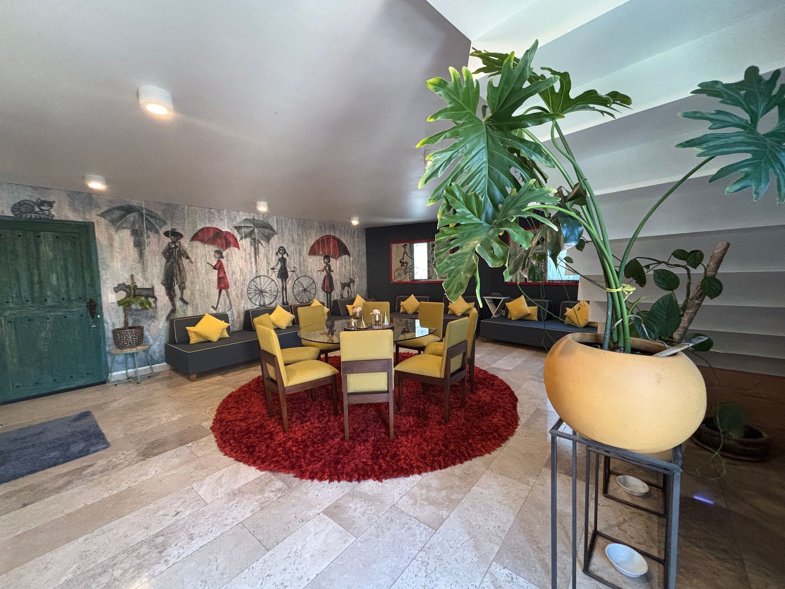 A modern living room with a round table, yellow chairs, and a red shag rug.