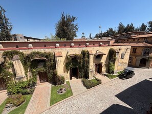 Un patio con edificios de piedra, arcos y un área pavimentada con un vehículo.
