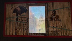 Un mural con una bicicleta, una persona bajo un paraguas y una ventana.