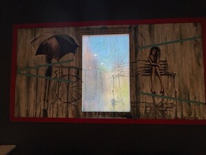A mural with a bicycle, a figure under an umbrella, and a window.