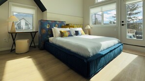 A bedroom with a bed, two bedside tables, a window, and a door.