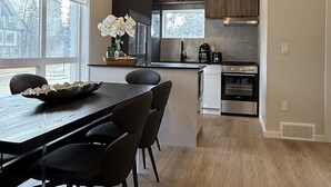 A modern kitchen with wooden cabinets, a central island, and a dining area with a table and chairs.