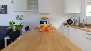 A modern kitchen with white cabinets, a wooden countertop, a coffee machine, and a fruit bowl. - Bungalow in Maspalomas near Golf & Beach (San Bartolomé de Tirajana)