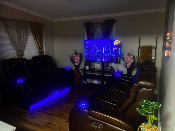 A living room with leather recliners, a flat-screen TV, and ambient blue lighting. - LED Lighting Reclining Sofas - Cozy 3 Bedroom Home In Jacksonville fl (Jacksonville)