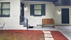 A house with a front porch, a bench, and a small garden area. - LED Lighting Reclining Sofas - Cozy 3 Bedroom Home In Jacksonville fl (Jacksonville)