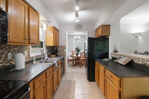 Una cocina con armarios de madera, un refrigerador negro y un salpicadero de azulejos.