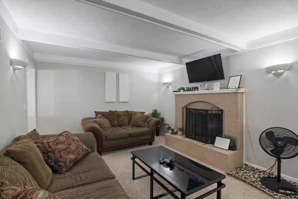 A living room with a fireplace, a television mounted above it, a sofa, and a coffee table.