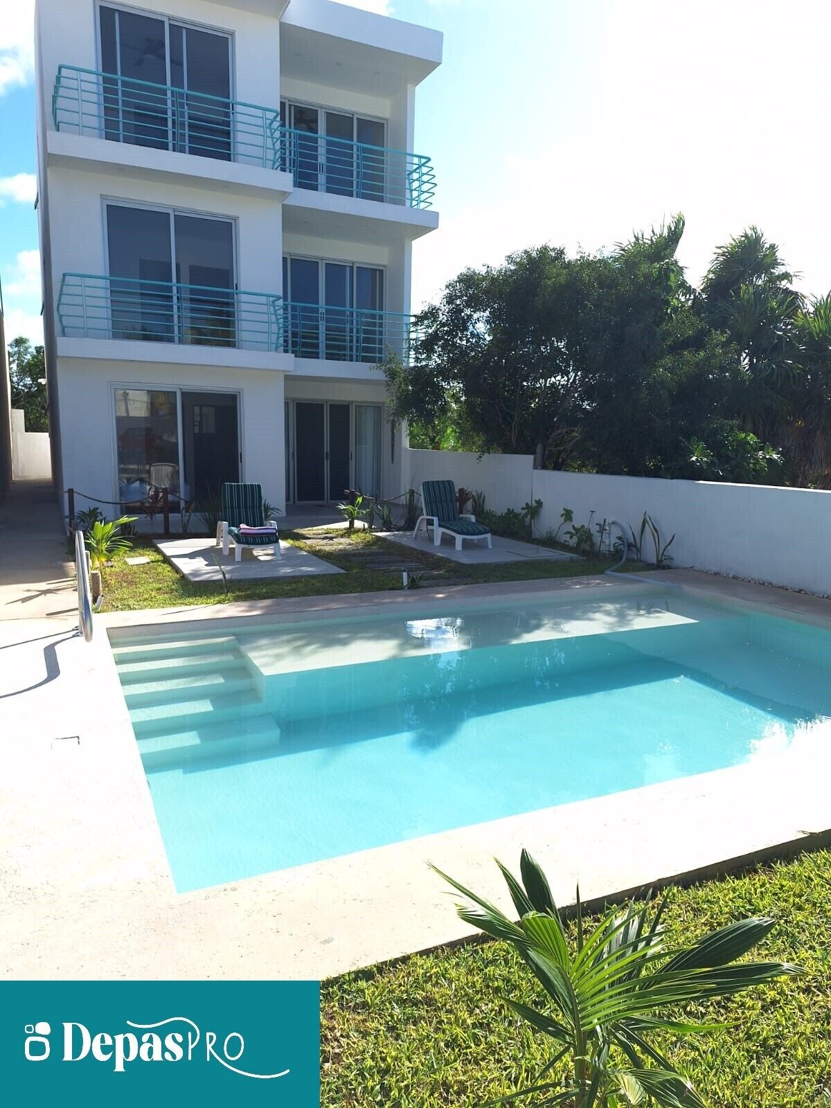 Um edifício moderno de dois andares com piscina, área de estar externa e um jardim bem cuidado.