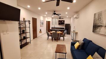 A modern living room with a blue sofa, a wooden coffee table, and a ceiling fan.