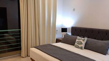 A bedroom with a bed, a ceiling fan, a nightstand, and a window with curtains.