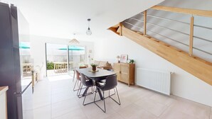A modern kitchen with a dining area, a staircase, and a view to the outside.