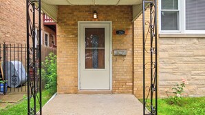 A brick building with a white door, a small porch, and a mailbox.