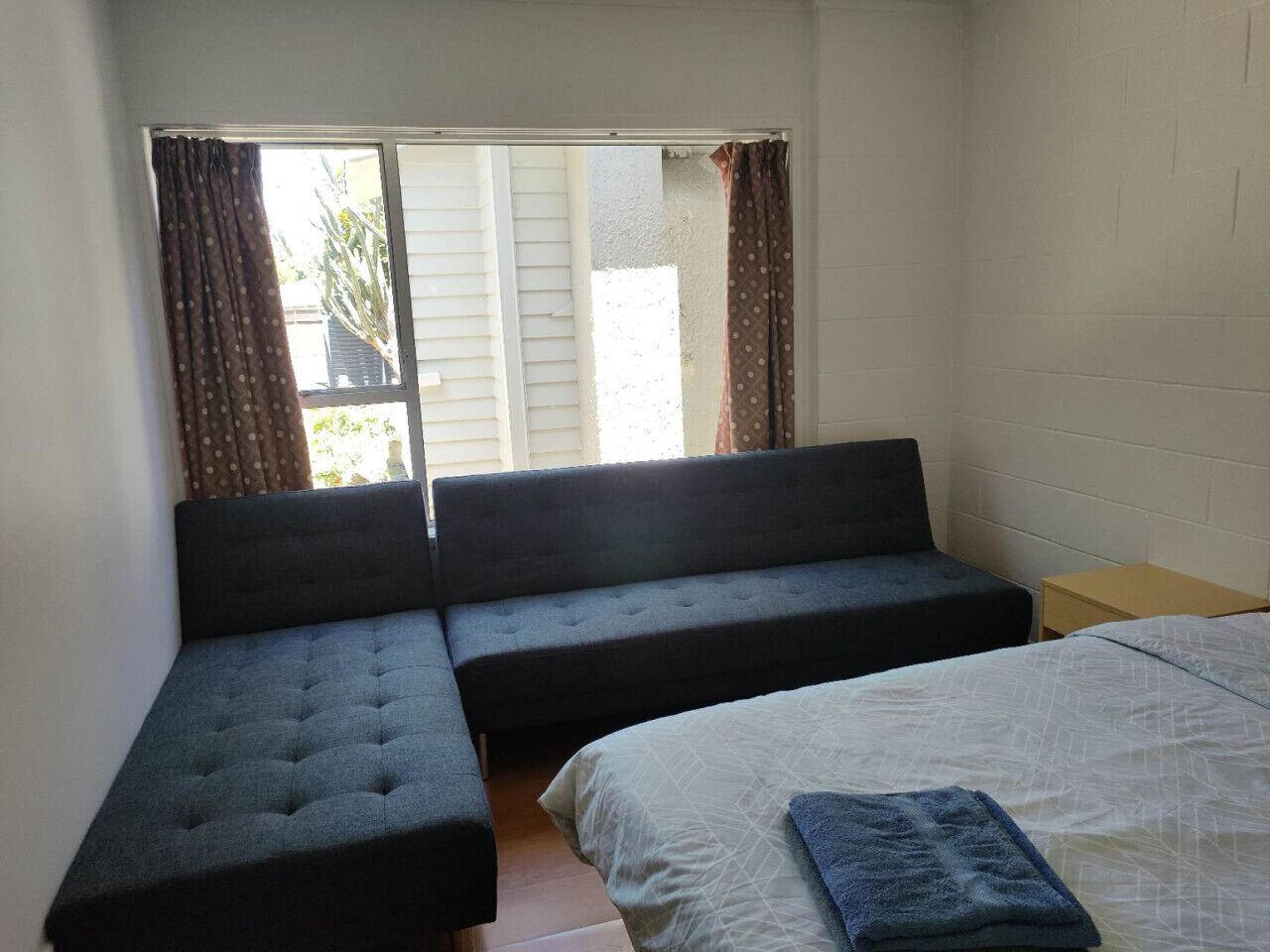Ein Zimmer mit einem Bett, einem Schlafsofa und einem Fenster mit Vorhängen.