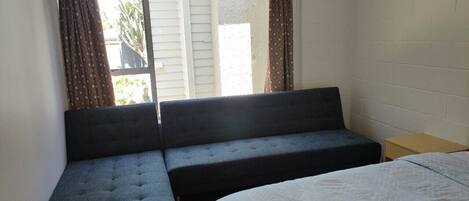 Ein Zimmer mit einem Bett, einem Schlafsofa und einem Fenster mit Vorhängen.