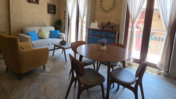 A dining area with a round table and chairs, a sofa with cushions, and a kitchen area with a counter and cabinets. - Loft Belterra (Val'Quirico)