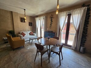 A cozy living room with a sofa, a yellow armchair, a dining table with chairs, and a hanging light fixture. - Loft Belterra (Val'Quirico)
