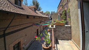 A narrow alley with buildings on either side, a tiled roof, and potted plants. - Loft Belterra (Val'Quirico)