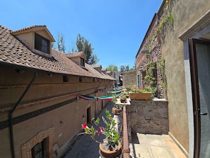A narrow alley with buildings on either side, a tiled roof, and potted plants. - Loft Belterra (Val'Quirico)