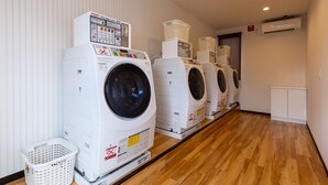 A row of stacked front-loading washing machines in a laundry room with wooden flooring and white walls. - HOTEL R9 The Yard Otawara (Otawara)