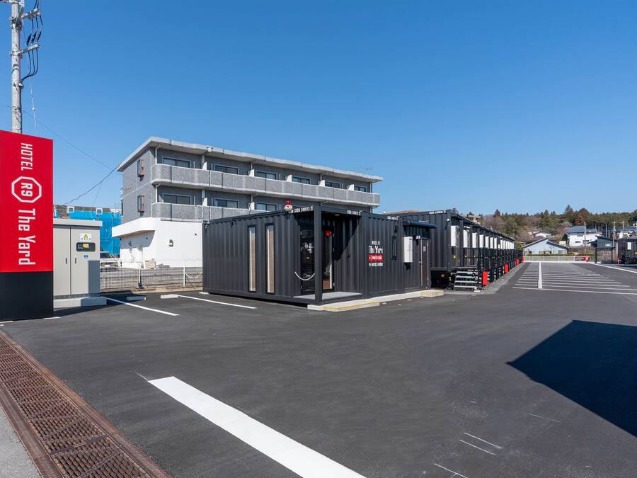 A modern hotel with a large building and shipping containers.