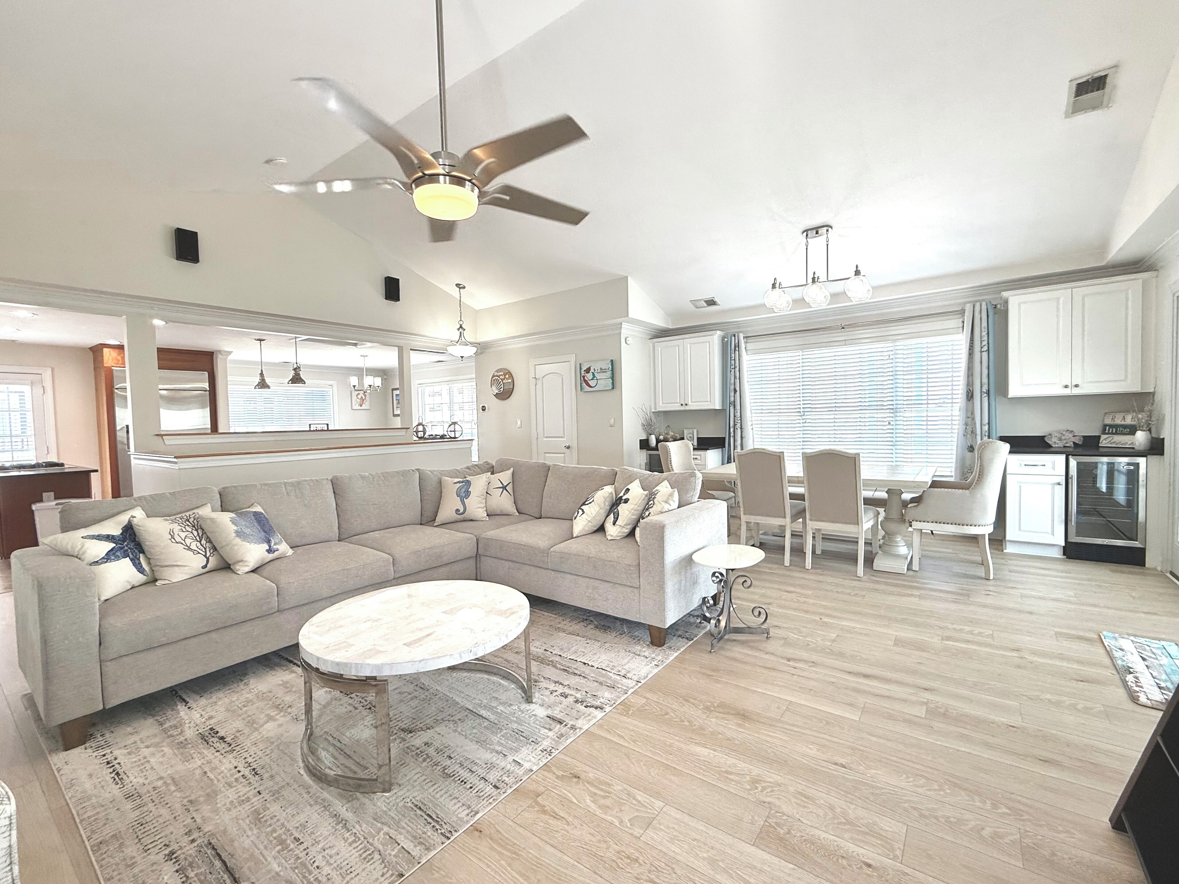 A spacious living room with a sectional sofa, a round coffee table, and a dining area with a table and chairs.