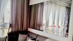 Uma sala de estar com um sofá seccional, um espelho grande e uma janela com cortinas.