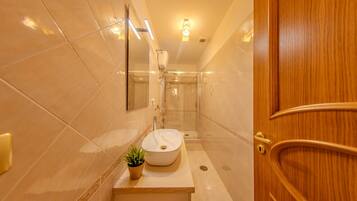 Un baño moderno con un espejo grande, un lavabo y una ducha.