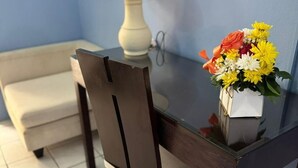 A dining table with a vase of flowers, a lamp, and a chair in a room with blue walls and tiled flooring. - The Palm (Gros Islet)
