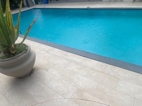 Una piscina al aire libre, sombrillas, sillones reclinables de piscina