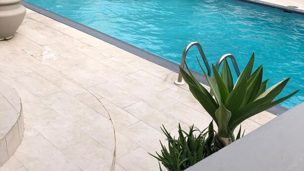 A swimming pool with a tiled deck and a metal ladder. - The Palm (Gros Islet)