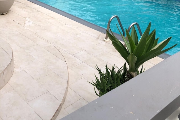 Una piscina al aire libre, sombrillas, sillones reclinables de piscina