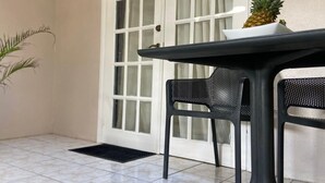 A small, enclosed outdoor area with a tiled floor, a table, two chairs, and a door with frosted glass panels. - The Palm (Gros Islet)