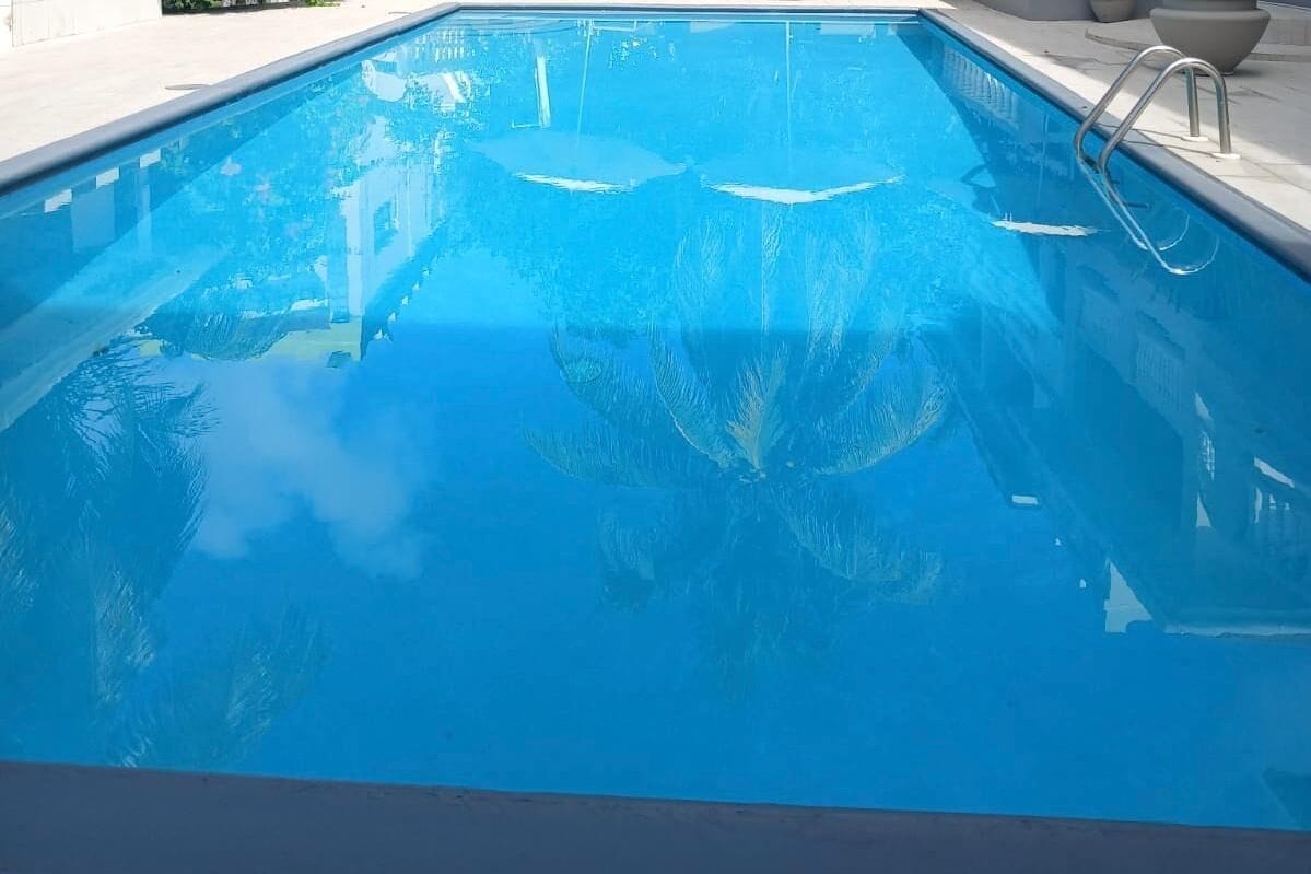 Una piscina al aire libre, sombrillas, sillones reclinables de piscina