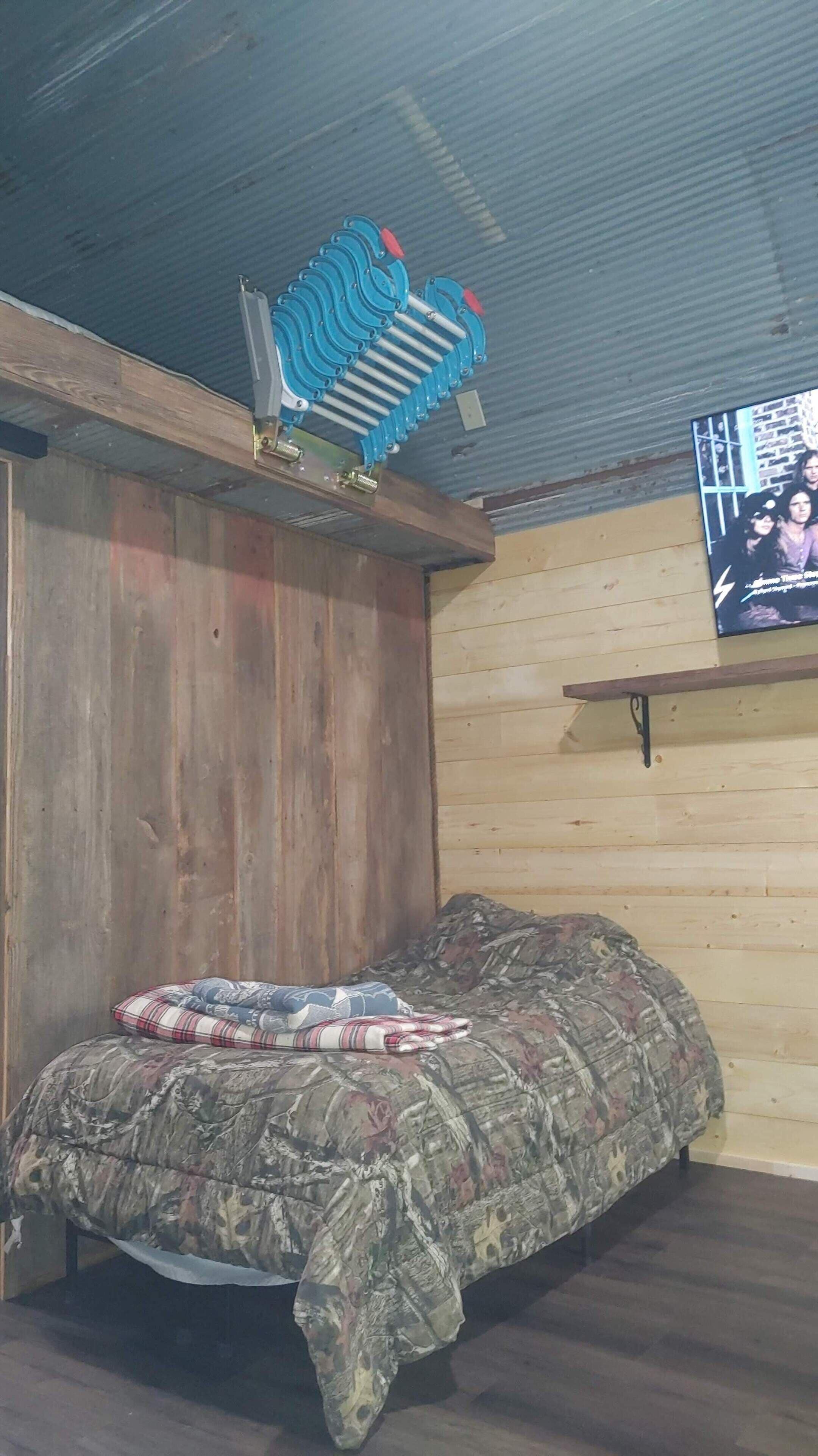 Quarto com cama, parede de madeira e ventoinha no teto.