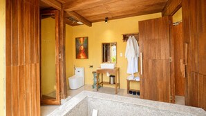 Un baño con techo de madera, inodoro blanco, lavamanos y bañera.