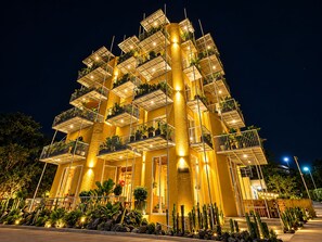 Un hotel de varios pisos con balcones, un patio central y una fachada bien iluminada.