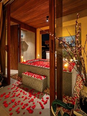A serene indoor setting with a stone bench surrounded by rose petals and candles, suggesting a romantic or intimate atmosphere. - Nexus House An Son Da Lat (Xuan Huong - Da Lat)