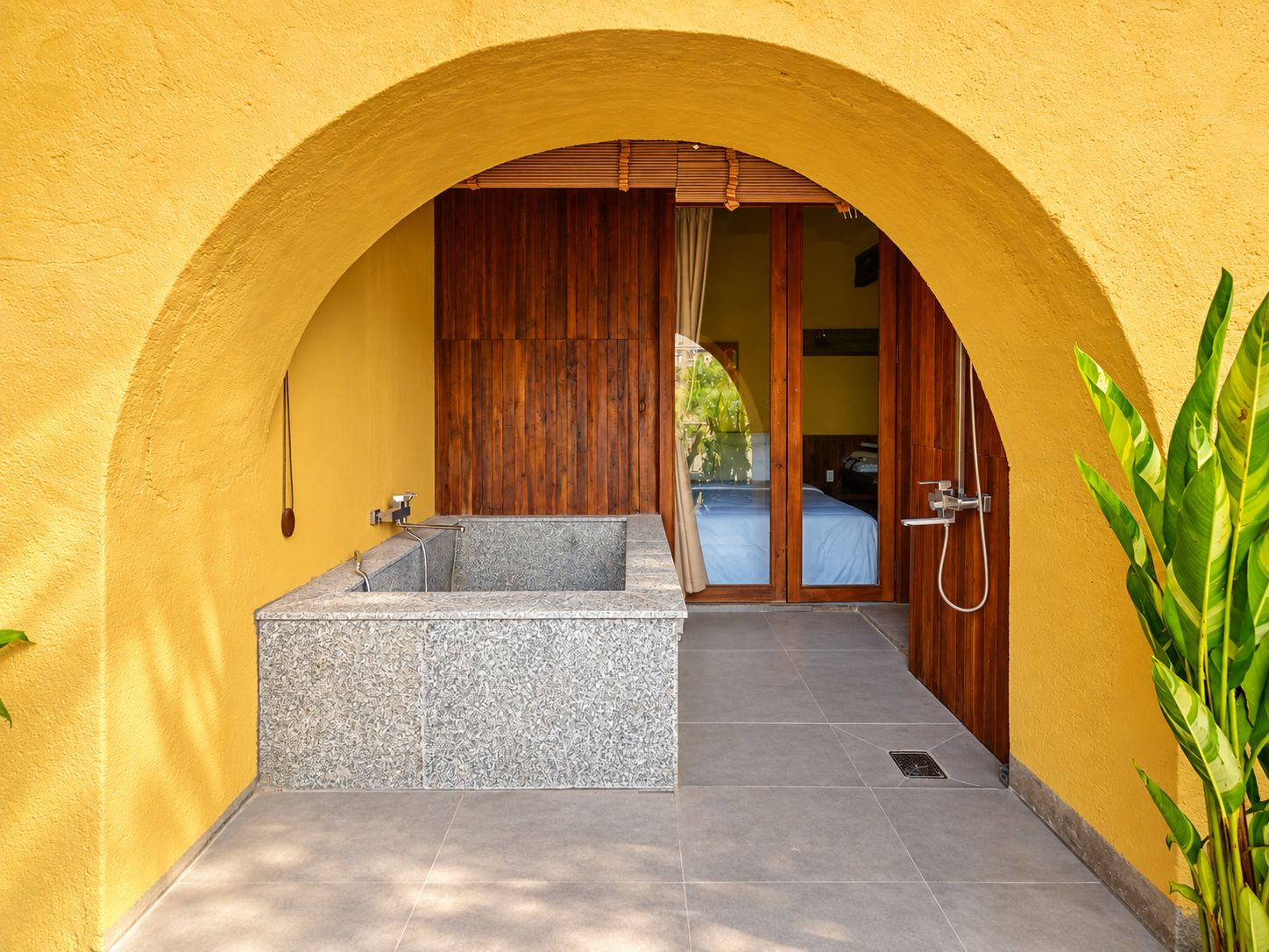 A spa area with a stone bathtub, wooden door, and a shower.