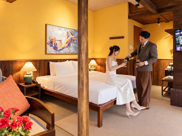 Habitación de hotel con cama, un cuadro en la pared, televisión y piso de madera.