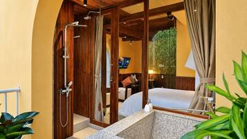 Ein Badezimmer mit Dusche, Waschbecken und einem Bett.
