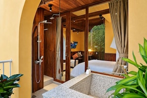 Een badkamer met een douche, wastafel en een bed.