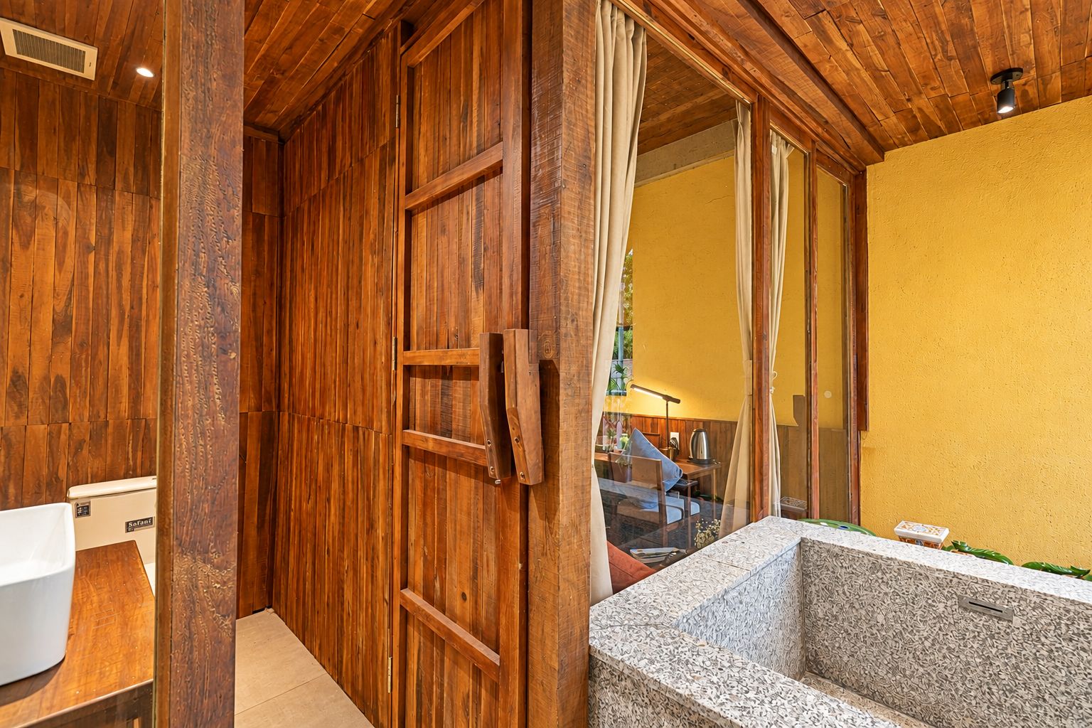 A bathroom with a wooden door, a bathtub, and a yellow wall.