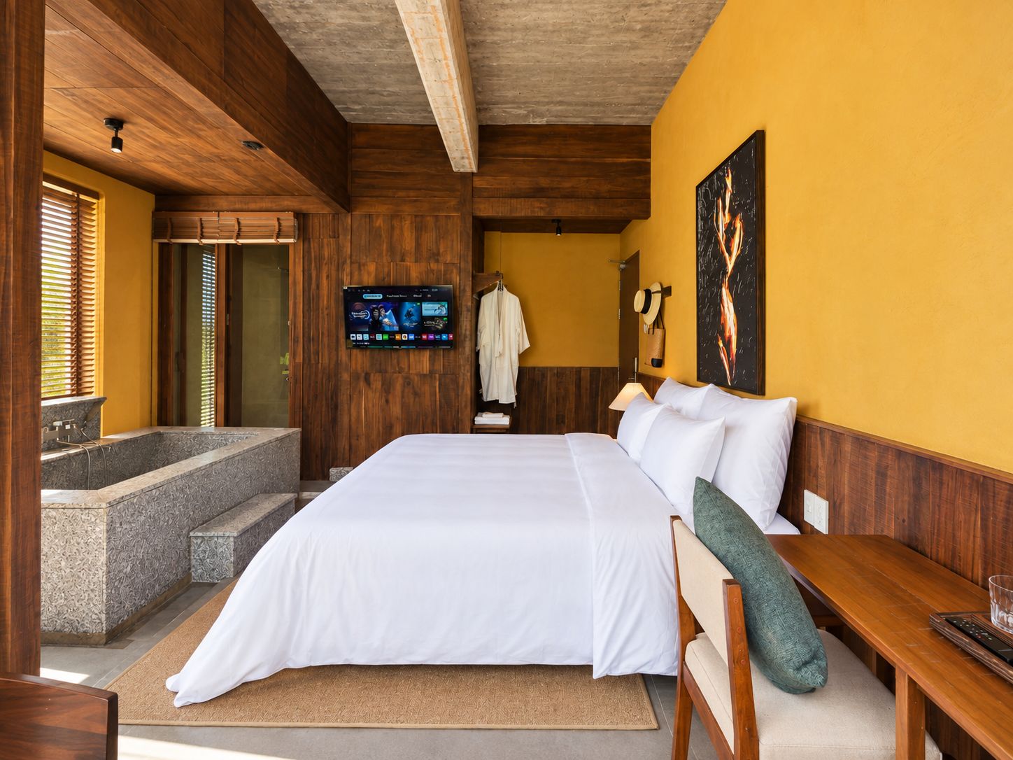 Une chambre d’hôtel avec un grand lit, un téléviseur à écran plat fixé au mur, un plafond en bois et une baignoire en pierre.