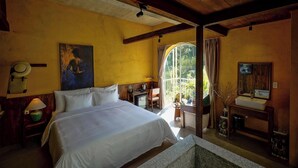 A bedroom with a bed, a desk, a small TV, and a window with curtains.