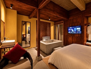 A hotel room with a large bed, a bathroom with a bathtub, a television on the wall, and wooden beams on the ceiling. - Nexus House An Son Da Lat (Xuan Huong - Da Lat)