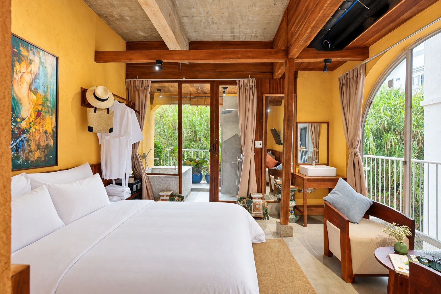 Habitación de hotel con una cama grande, un balcón con vistas, un baño con ducha y un comedor.