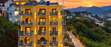 A multi-story hotel with balconies, a pathway, and a view of the surrounding landscape.