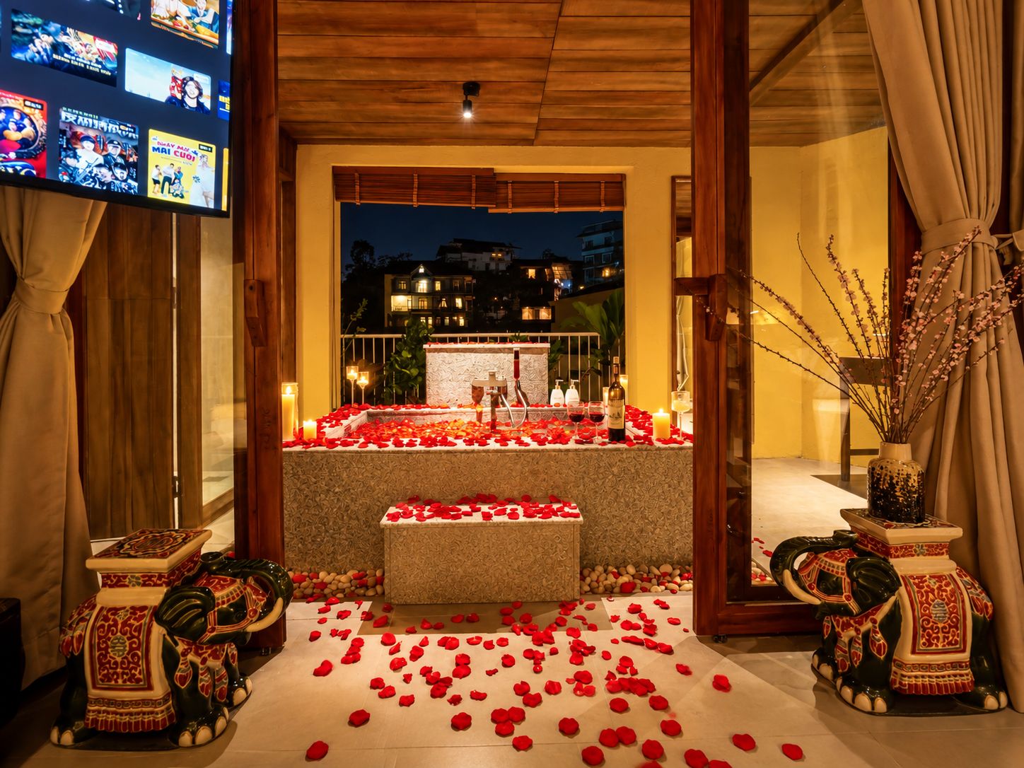 Ambiente romántico con pétalos de rosa, velas y una bañera en una habitación de hotel.