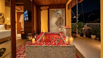 Una habitación con un banco de piedra, velas y pétalos de rosa.
